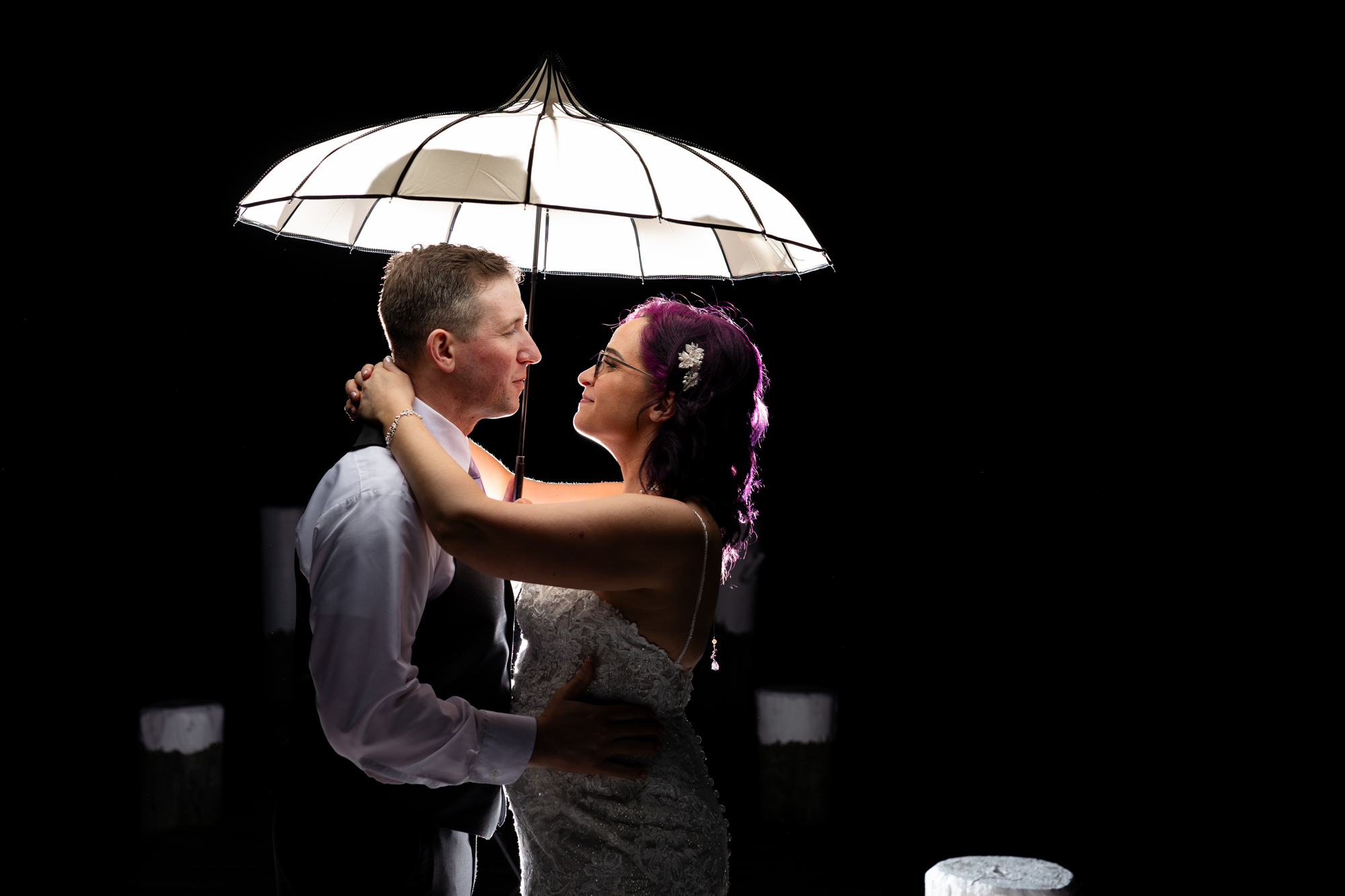 Wedding photography at Celebrations at the Bay. A beautiful bride & groom backlit with an umbrella at night.